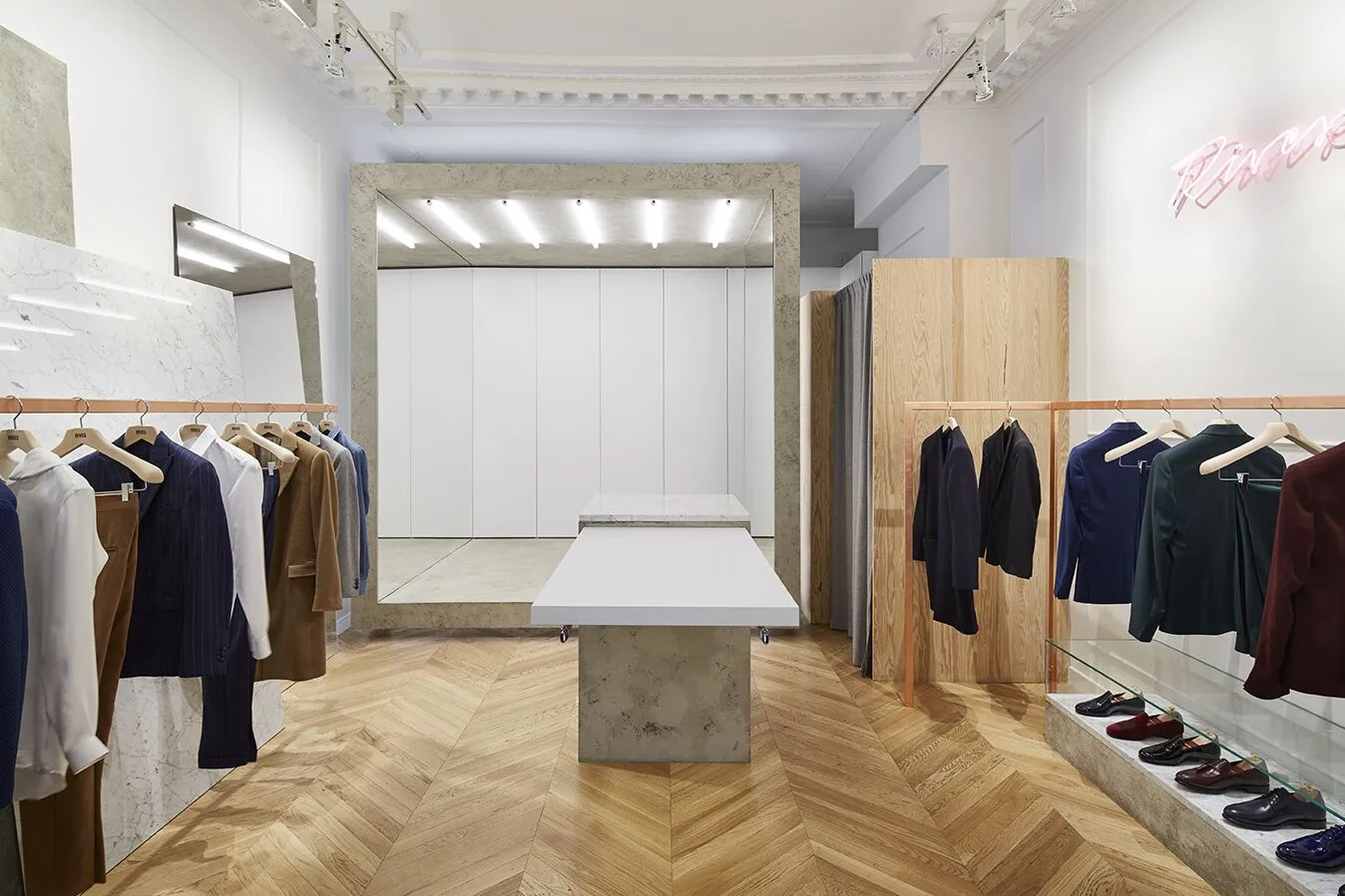 L'atelier-boutique, à Paris Intérieur de la boutique RIVES Paris, atelier de tailleur sur-mesure avec parquet à chevrons, marbre et portants de costumes.